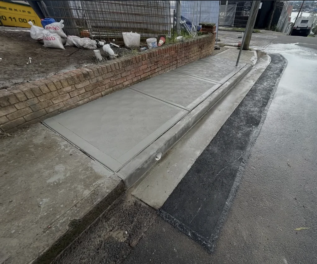 Concrete footpath and kerb beside a brick wall at Abbotsford